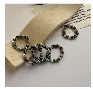 Macro detail of S925 silver beaded rings with natural spotted stone on beige stone base