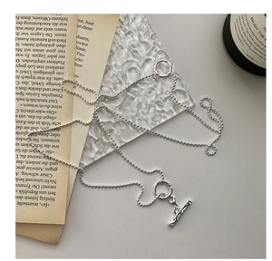 Détail du collier à billes argentées avec fermoir à bascule OT sur verre texturé
