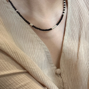 S925 sterling silver beaded necklace with black onyx accents worn on a beige shirt