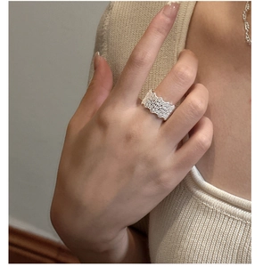 Detailed view of wide silver lace-style ring with scalloped edges and hollow lattice pattern