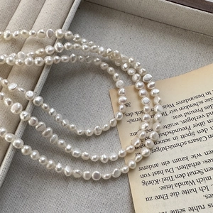 Irregular baroque pearl necklace on a gray jewelry box with vintage paper decor