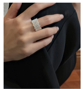 Macro detail of S925 sterling silver wide ring with delicate lace textured hollow design