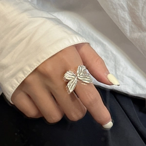 S925 sterling silver bow ring with textured wings shown on finger in a minimalist macro shot