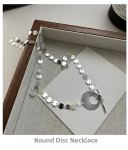 Détail d'un collier à paillettes argentées avec pendentif rond et fermoir OT élégant