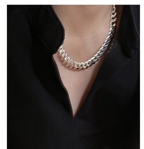 Détail d'un collier chaîne gourmette épaisse en argent S925 porté sur un col montant noir