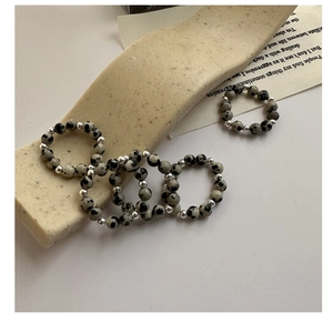 Macro detail of S925 silver beaded rings featuring natural dalmatian stone on beige stand