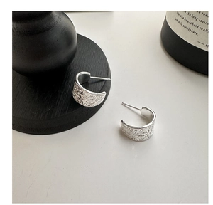 Détail macro des boucles d'oreilles C en argent S925 avec gravure florale précise