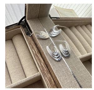 Macro shot of silver layered wave earrings in a beige velvet jewelry storage box