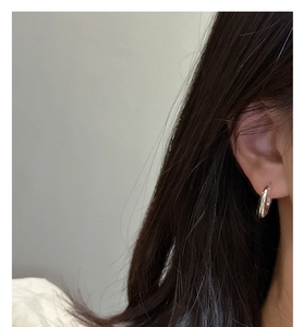 Close-up of a minimalist S925 sterling silver C-shaped hoop earring worn by a model