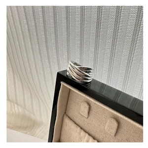 Détail d'une bague large argentée multicouche avec des lignes entrelacées lisses