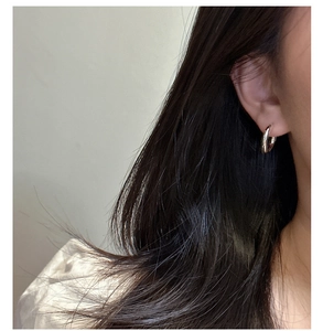Close-up of minimalist S925 sterling silver C-shaped hoop earring on a model ear