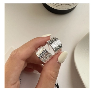 Détail de boucles d'oreilles en argent S925 en forme de C avec gravure florale en relief