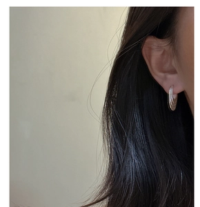 Close-up of S925 sterling silver multi-layer circular hoop earrings on model ear