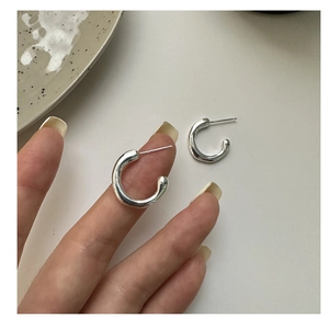 Close-up of irregular C-shaped S925 sterling silver earrings with fluid organic design
