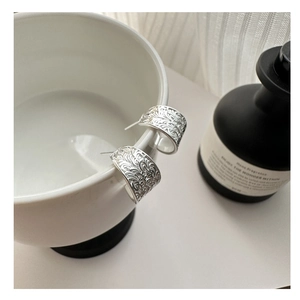 Détail de boucles d'oreilles créoles en argent S925 avec textures florales en relief