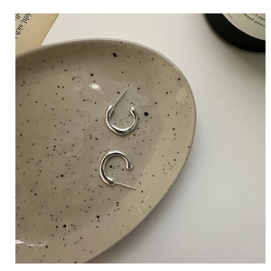 Minimalist S925 silver C-shape earrings displayed on an artistic ceramic tray