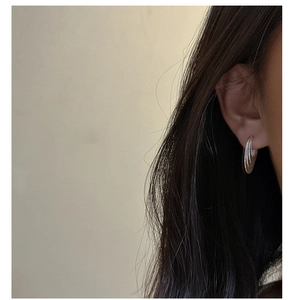Close-up of S925 sterling silver curved layered earrings worn by a model in soft light