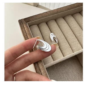 Close-up of S925 sterling silver curved wave stud earrings in a wooden jewelry box