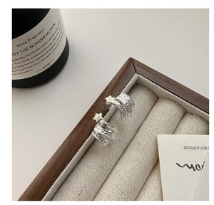 Détail de boucles d'oreilles étoile en argent S925 dans un coffret en velours beige