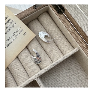 Detail of S925 sterling silver curved wave earrings displayed in a wooden jewelry box