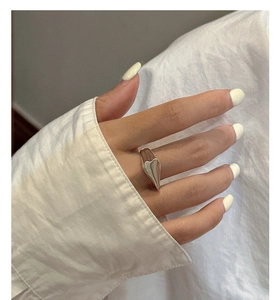 Close-up of wide polished S925 sterling silver heart ring worn on finger