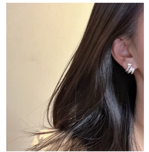 Gros plan de boucles d'oreilles étoile en argent au design épuré portées par un mannequin