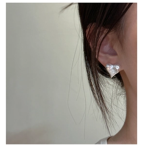 Detailed close-up of textured heart stud earrings with a melted silver lava finish