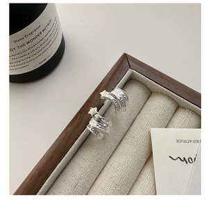 Détail de boucles d'oreilles étoile en argent S925 avec lignes texturées en forme de C