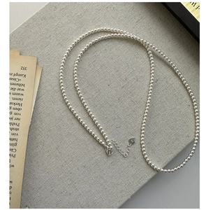 Detail of 925 sterling silver heart clasp and small white pearls on linen background