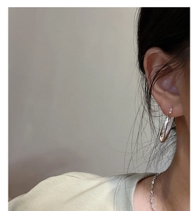 Gros plan d'une boucle d'oreille créole épaisse en argent S925 poli sur une oreille