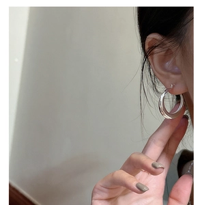 Vue macro de boucles d'oreilles créoles en argent S925 poli portées par un mannequin