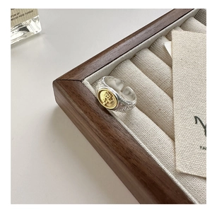 Detailed close-up of a silver tree of life ring with gold emblem on a linen holder