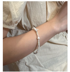 Detail of s925 silver bracelet with irregular pearls, pink gems and heart charm on wrist