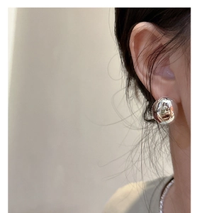 Close-up of a high-polish silver oval stud earring on model with minimalist design