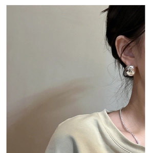 Polished silver sphere stud earrings on model with elegant side lighting and macro detail