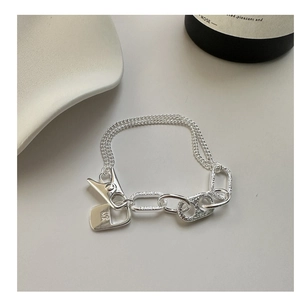 Close-up of S925 silver bracelet featuring mixed chains and a unique binder clip charm