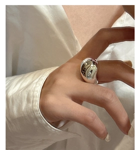 Close-up of a minimalist S925 silver wide-band irregular bean ring on a finger