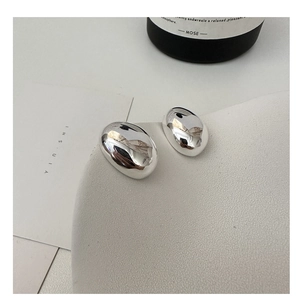 Macro view of minimalist polished silver oval stud earrings with reflective mirror finish