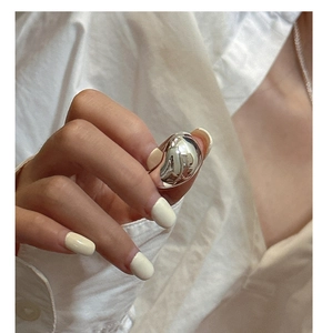 Close-up of minimalist chunky silver dome ring on finger with mirror-like finish