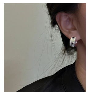 Close-up of matte silver hoop earring with black zircon detail on a model's ear