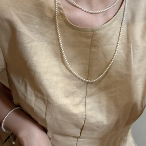 Elegant 925 silver layered pearl necklace and bracelet set on model in linen attire