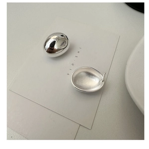 Detail showing S925 hallmark on polished silver oval studs with matte texture
