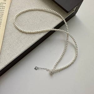 925 sterling silver pearl necklace with S925 heart charm on soft beige canvas background