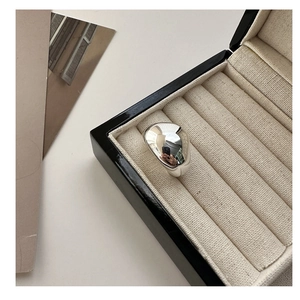 Close-up of a silver liquid metal blob ring on a velvet cushion with a soft aesthetic