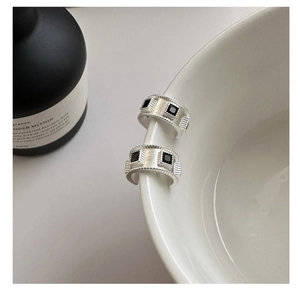 Macro shot of silver matte brushed hoop earrings with square black zircon inlay