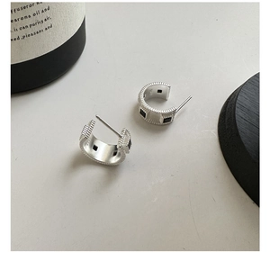 Macro shot of S925 sterling silver C-shaped earrings featuring textured stripes and black zircon
