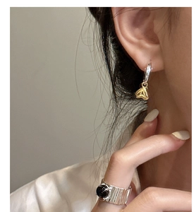 Dettaglio di orecchini a cuore in argento S925 e un anello a fascia con pietra nera