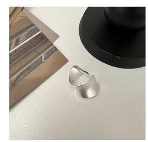 Détail de bague ouverte argentée mate au design minimaliste avec courbes irrégulières