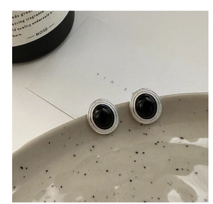Macro view of vintage silver oval earrings with black onyx inlay on ceramic plate