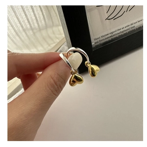 Dettaglio di orecchini a cerchio in argento S925 con pendente a cuore d'oro in mano